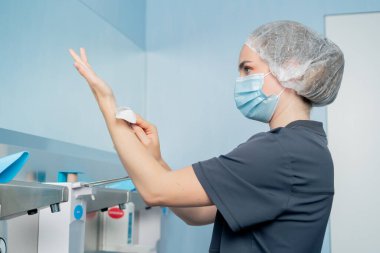 Cerrahların ellerini sterilize etmek için geniş bir alanda modern bir klinikte kadın cerrah ellerini iyice yıkıyor.