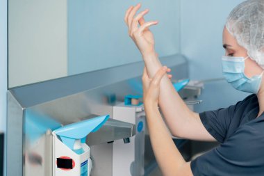 Cerrahların ellerini sterilize etmek için geniş bir alanda modern bir klinikte kadın cerrah ellerini iyice yıkıyor.