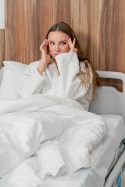 Modern bir klinikte, parlak bir VIP odasında, soğuk algınlığı olan beyaz önlüklü genç bir kız yatıyor.