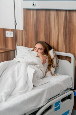 Modern bir klinikte, parlak bir VIP odasında, soğuk algınlığı olan beyaz önlüklü genç bir kız yatıyor.