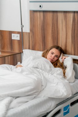 Modern bir klinikte, parlak bir VIP odasında, soğuk algınlığı olan beyaz önlüklü genç bir kız yatıyor.