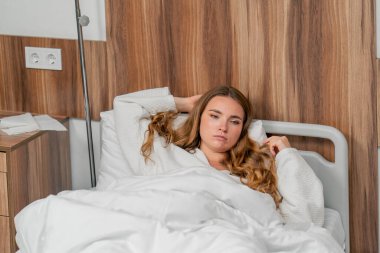 Modern bir klinikte, parlak bir VIP odasında, soğuk algınlığı olan beyaz önlüklü genç bir kız yatıyor.