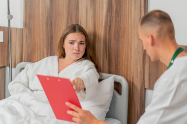 Modern bir klinikte, parlak bir VIP odasında, beyaz önlüklü genç bir kız hasta, bir doktorla görüşüyor, tedavi önerileri...