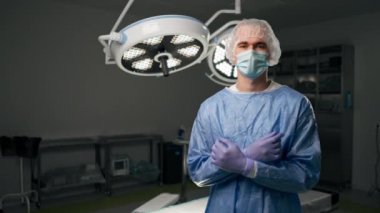 Modern bir klinikte, parlak, geniş bir ameliyathanede cerrah ameliyatı yapmak için tamamen hazırdır.