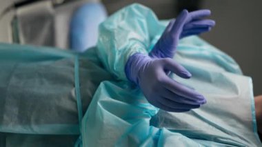 Parlak, geniş bir ameliyathanede, modern bir klinikte, dikey video eller. Cerrah ameliyatı ameliyathanede yapmaya tamamen hazır.