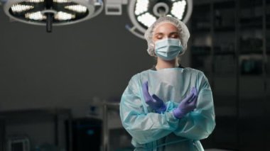 Modern bir klinikte, parlak, geniş bir ameliyathanede cerrah ameliyatı yapmak için tamamen hazırdır.