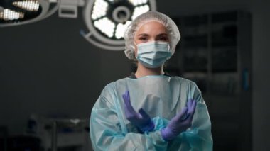 Modern bir klinikte, parlak, geniş bir ameliyathanede cerrah ameliyatı yapmak için tamamen hazırdır.