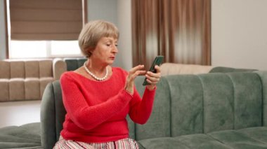 Modern bir klinikte, bekleme odasında, mercan kazaklı yaşlı bir kadın yeşil kadife koltukta oturuyor, doktorun aramasını bekliyor, telefonundan haberleri okuyor.
