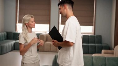 Modern bir klinikte, bekleme odasında, hafif elbiseli genç bir kız, sonuçlarla doktora yaklaşır ve sağlık sorunu hakkında konuşur.