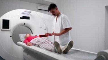 Modern bir klinikte, beyaz bir ofiste yaşlı bir kadının, yakınlardaki genç bir doktorun beyin MR 'ı için bir ilaç.