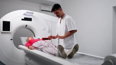Modern bir klinikte, beyaz bir ofiste yaşlı bir kadının, yakınlardaki genç bir doktorun beyin MR 'ı için bir ilaç.