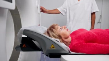 Modern bir klinikte, beyaz bir ofiste yaşlı bir kadının, yakınlardaki genç bir doktorun beyin MR 'ı için bir ilaç.