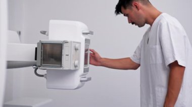 Beyaz bir ofisteki modern bir klinikte florografi hazırlığı, hastaların güvenli bir şekilde incelenmesi için en son teknolojiler, doktorun makineyi çalıştırması.