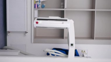 Modern bir klinikte dikey video kapanıyor, beyaz bir ofiste, florografi görüntüleri için bir hazırlık, en son teknolojiler hastaların güvenli bir şekilde incelenmesi için doktor makineyi açıyor.