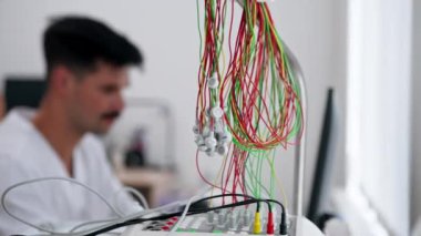 Modern bir klinikte, beyaz kalp atış hızı tarama odasında, kalp atışlarını kontrol etmek için bir ilaç, kardiyogram, bilgiyi bir doktor doldurur.