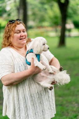 Yazın parkta yürürken şişman yaşlı bir kadın, hayvanlara olan sevgisiyle Maltalı bir köpeği kucağına alır. Parkta sahibinin bakımıyla yürür.