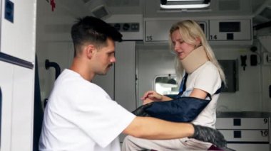 Ambulansta yaralı bir boyun ve kolla genç bir hasta kliniğe naklediliyor yaralı bir kolu kontrol eden genç bir doktor.