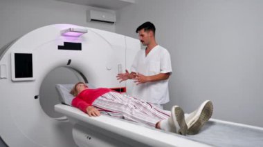 Modern bir klinikte, beyaz bir ofiste yaşlı bir kadının, yakınlardaki genç bir doktorun beyin MR 'ı için bir ilaç.