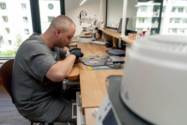 Diş protezlerinin üretimi için profesyonel laboratuvar kaplamaları ve taçlandırması. Bir uzman bir tacı insan çene çene şekli profesyonel ekipman biçimine ayarlar.