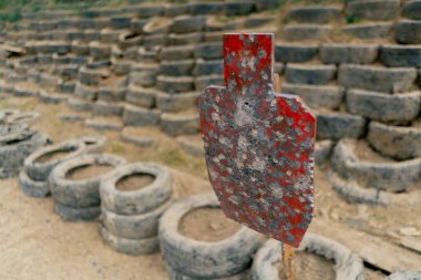 Profesyonel bir atış poligonunda, kumlu zemin, otomobil lastikleri duvarı, demir delici hedef, profesyonel atış poligonu, eğitim askerleri, kurşun koruması
