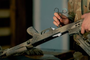 Profesyonel bir atış poligonunda, bir ağaç standında, bir antrenör Amerikan makineli tüfeğinin sökülmesi ve temizlenmesi hakkında talimatlar verir.