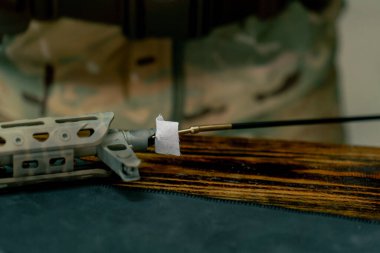 Profesyonel bir atış poligonunda, bir ağaç standında, bir antrenör Amerikan makineli tüfeğinin sökülmesi ve temizlenmesi hakkında talimatlar verir.