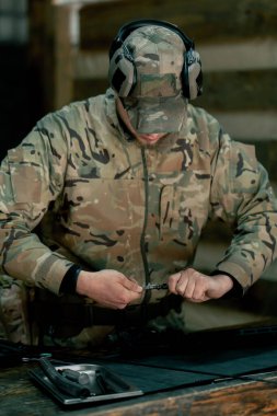 Profesyonel bir atış poligonunda, bir ağaç standında, bir antrenör Amerikan makineli tüfeğinin sökülmesi ve temizlenmesi hakkında talimatlar verir.