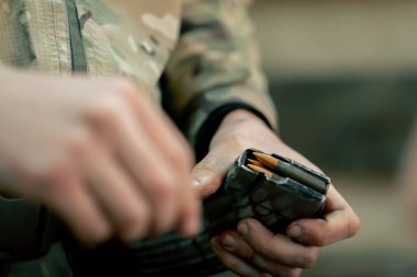Profesyonel atış poligonuna yakın çekim yapan askeri üniformalı bir eğitmen profesyonel atış poligonunda makineli tüfek gösterisi için şarjör dolduruyor.