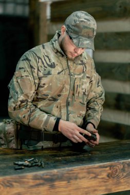 Profesyonel atış poligonu. Askeri üniformalı bir askeri eğitmen profesyonel atış poligonunda makineli tüfek gösterisi için şarjör dolduruyor.