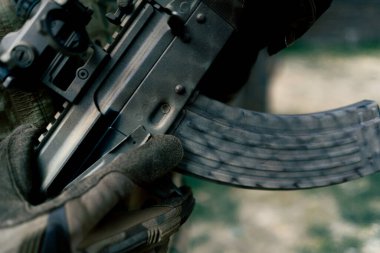 Askeri taktik stratejisi NATO tüfek pozisyonu. Askeri üniformalı profesyonel bir poligon eğitimcisine silah eğitimini yeniden yüklemek için. Bir şarjörü fişeklerle değiştirmek için.