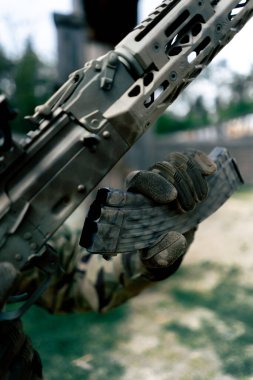 Askeri taktik stratejisi NATO tüfek pozisyonu. Askeri üniformalı profesyonel bir poligon eğitimcisine silah eğitimini yeniden yüklemek için. Bir şarjörü fişeklerle değiştirmek için.