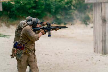 Profesyonel atış alanında eğitim alanında iki askeri eğitmen makineli tüfekle taktik tatbikat yapıyor.
