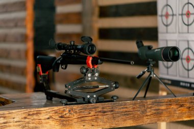 Profesyonel atış poligonunda, ahşap masadaki profesyonel tüfek, geniş kalibreli av tüfeği, modern savaş teknolojisi.