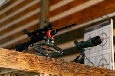 Profesyonel atış poligonunda, ahşap masadaki profesyonel tüfek, geniş kalibreli av tüfeği, modern savaş teknolojisi.