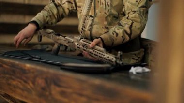 Profesyonel bir atış poligonunda, bir ağaç standında, bir antrenör Amerikan makineli tüfeğinin sökülmesi ve temizlenmesi hakkında talimatlar verir.