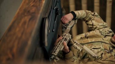 Profesyonel bir atış poligonunda, ağaç tezgahında dikey bir video, bir antrenör Amerikan makineli tüfeğinin sökülmesi ve temizlenmesi hakkında talimatlar verir.