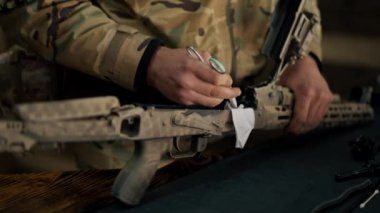 Profesyonel bir atış poligonunda, bir ağaç standında, bir antrenör Amerikan makineli tüfeğinin sökülmesi ve temizlenmesi hakkında talimatlar verir.