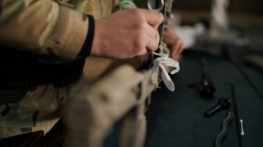 Profesyonel bir atış poligonunda, bir ağaç standında, bir antrenör Amerikan makineli tüfeğinin sökülmesi ve temizlenmesi hakkında talimatlar verir.
