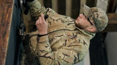 Profesyonel bir atış poligonunda, bir ağaç standında, bir antrenör Amerikan makineli tüfeğinin sökülmesi ve temizlenmesi hakkında talimatlar verir.
