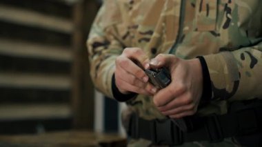 Profesyonel atış poligonuna yakın çekim yapan askeri üniformalı bir eğitmen profesyonel atış poligonunda makineli tüfek gösterisi için şarjör dolduruyor.