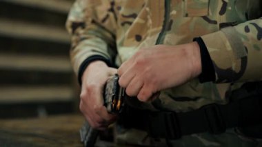Profesyonel atış poligonuna yakın çekim yapan askeri üniformalı bir eğitmen profesyonel atış poligonunda makineli tüfek gösterisi için şarjör dolduruyor.