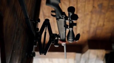 Profesyonel atış menzilinde dikey video yakın çekim, ahşap masa üzerinde profesyonel tüfek, geniş kalibreli av tüfeği, modern savaş teknolojileri.