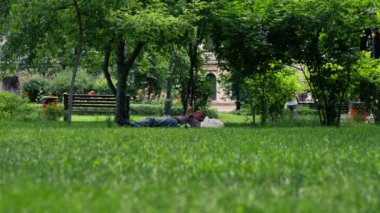 Ziyaretçiler için park alanı, yeşil çim biçme çimenliği geniş çalı bitkileri ile yürüme köpekleri, çitli bölge evsiz adam yalan