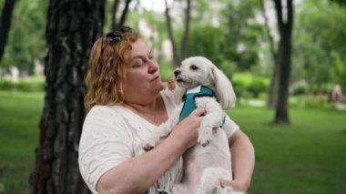 Yazın parkta yürürken şişman yaşlı bir kadın, hayvanlara olan sevgisiyle Maltalı bir köpeği kucağına alır. Parkta sahibinin bakımıyla yürür.