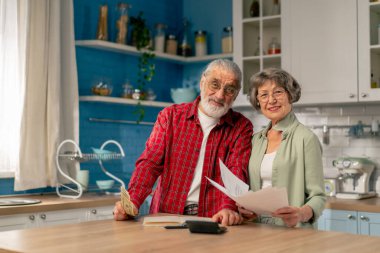 Parlak bir mutfakta, masadaki yaşlı, sevimli bir çift aylık giderlerini hesaplar. Yıllık giderlerini hesaplarlar. Aylık hayatta kalma paralarını gülerek sayarlar.