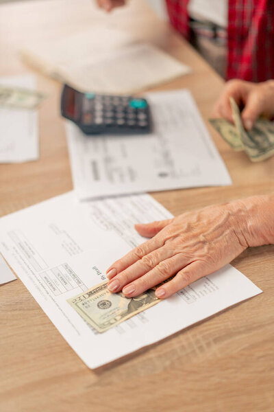 close-up in a bright kitchen hands with American bills calculator payment receipts calculator hard pension utilities