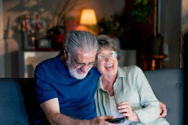 Parlak oturma odasını kapatın. Büyükanneniz ve büyükbabanız televizyon seyrediyor. Yaşlı çiftlerin boş zamanlarında kanalı değiştiriyorlar.