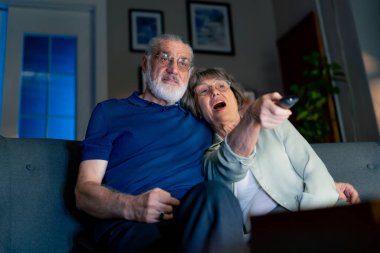 Parlak oturma odasını kapatın. Büyükanneniz ve büyükbabanız televizyon seyrediyor. Yaşlı çiftlerin boş zamanlarında kanalı değiştiriyorlar.