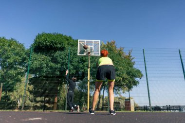 Spor sahası basketbol sahasında kısa şortlu, sarı tişörtlü basketbol oynayan siyah saçlı kız basketbol oynuyor.