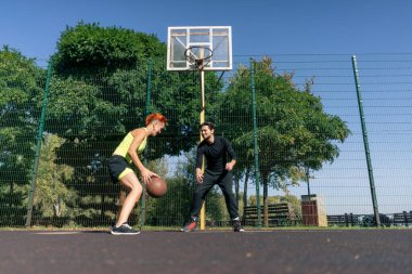 Spor sahası basketbol sahasında kısa şortlu, sarı tişörtlü basketbol oynayan siyah saçlı kız basketbol oynuyor.